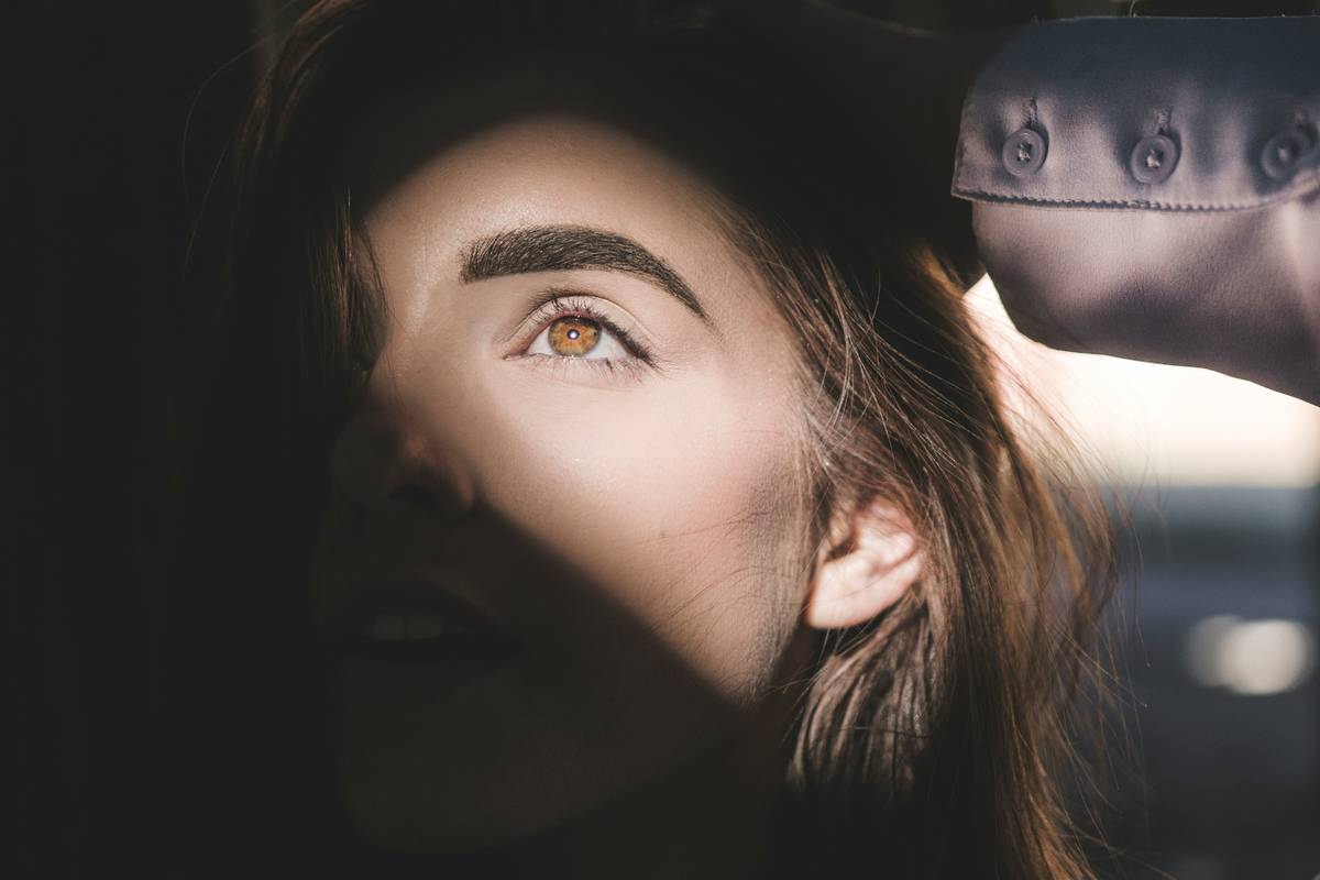 Close-up of professional eyebrow cutting scissors trimming fine brow hairs with precision
