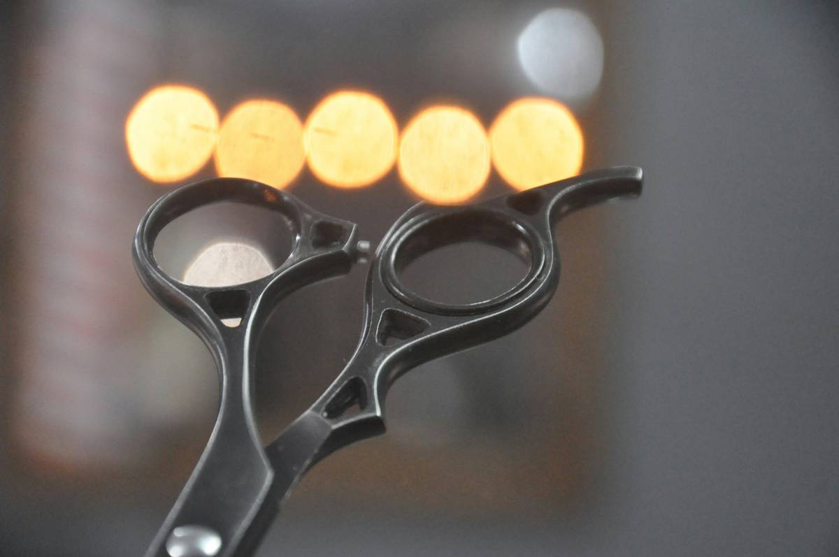 Close-up of stainless steel brow styling tool trimming fine eyebrow hairs